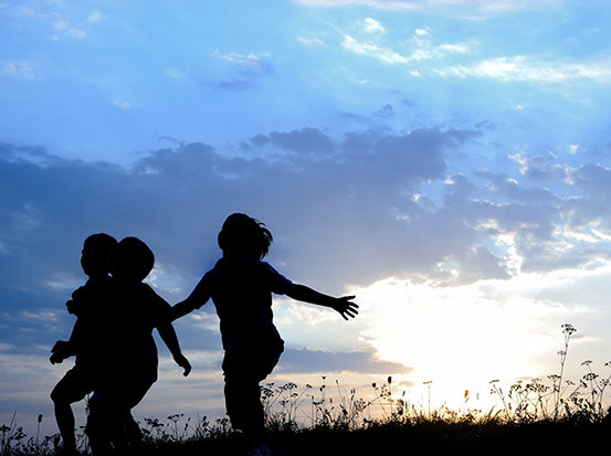Children playing silhouetted against sunset